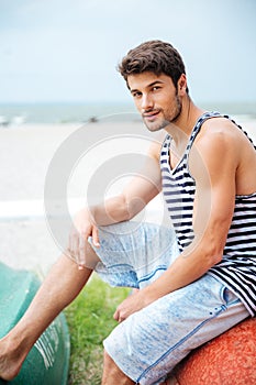 Handsome young man sitting on a fishing boat by sea