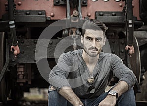 Handsome young man sitting in front of old train