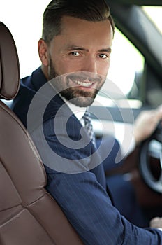 Handsome young man sitting in the front seat of a car looking at the camera