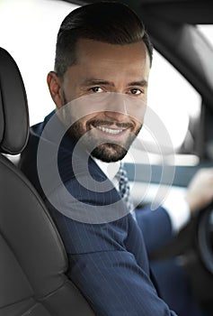 Handsome young man sitting in the front seat of a car looking at the camera