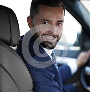 Handsome young man sitting in the front seat of a car looking at the camera