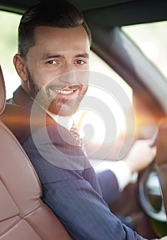 Handsome young man sitting in the front seat of a car looking at the camera