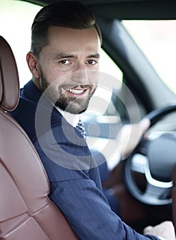 Handsome young man sitting in the front seat of a car looking at the camera