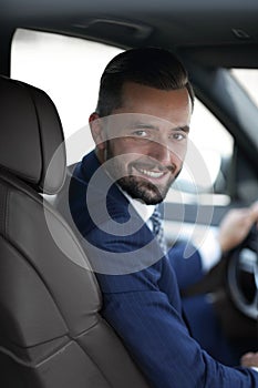 Handsome young man sitting in the front seat of a car looking at the camera