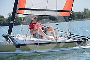 Handsome young man sitting on hobie cat