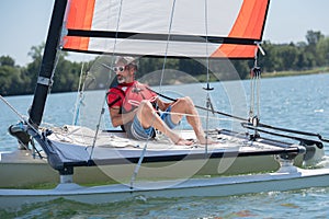 Handsome young man sitting on hobie cat photo