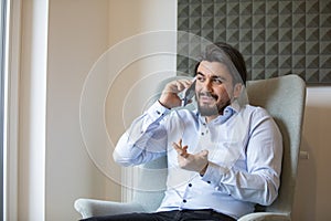 Handsome young man sitting at home while talking on the phone