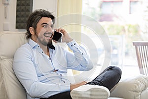 Handsome young man sitting at home while talking on the phone