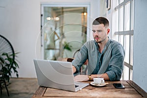 A Handsome young man sitting on laptop reading online news. freelance concept