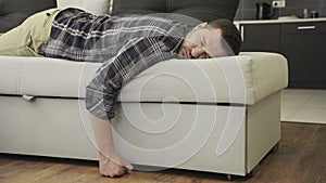 Handsome young man sleeping on the couch in his living room at home. Slow motion