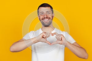 Handsome young man, smiles and makes a heart-shaped symbol with his finger