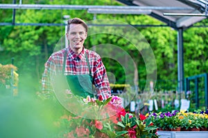 Handsome young man smiling happy while working as florist in a m