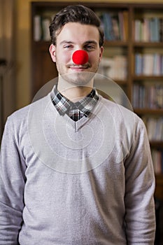 Handsome young man smiling with red clown nose
