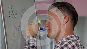 Handsome young man solving math problem on whiteboard