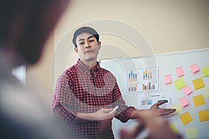 Handsome young man standing near whiteboard and pointing on the chart presentation