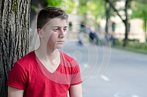 Handsome young man standing beside tree outdoor in spring