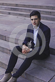 Handsome young man with styled hair. The man is sitting on the steps.