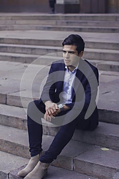 Handsome young man with styled hair. The man is sitting on the steps.