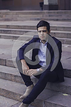 Handsome young man with styled hair. The man is sitting on the steps.