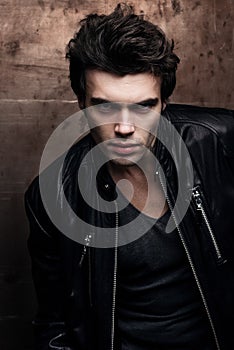 Handsome young man in stylish black leather jacket. Fashion model in dark clothes