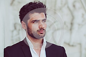 Handsome and young man with stylish hair and beard. Portrait of charming man. White shirt and jacket photo