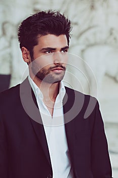 Handsome and young man with stylish hair and beard. Portrait of charming man. White shirt and jacket photo