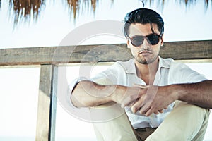 Handsome young man with sunglasses sitting photo