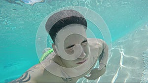 Handsome young man swimming in pool, underwater shot