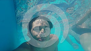 Handsome young man swimming in pool, underwater shot