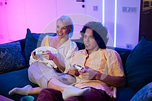 Handsome young man teaching how to play the video games to his girlfriend, on the couch, concept about home