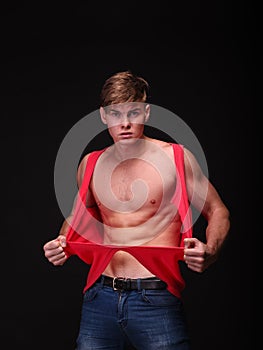 handsome young man tearing shirt off on a black background. Fitness and workout concept.