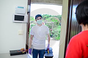 Handsome young man telephone operator worker fixing internet issue connexion at client house with surgical mask and gloves COVID19