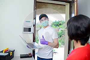 Handsome young man telephone operator worker fixing internet issue connexion at client house with surgical mask and gloves COVID19