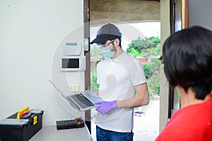 Handsome young man telephone operator worker fixing internet issue connexion at client house with surgical mask and gloves COVID19