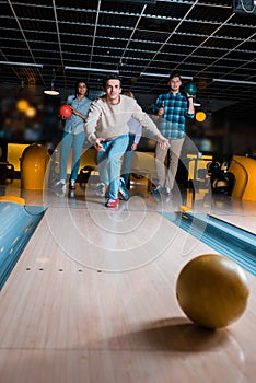 Handsome young man throwing bowling ball