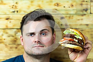 Handsome young man about to enjoy his burger. Fast food goodies