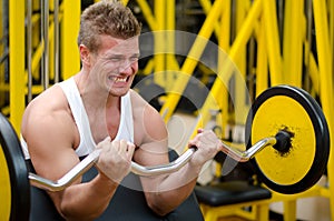 Handsome young man training biceps in gym