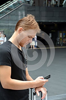 Handsome young man traveling on Kyoto and looking at his mobile phone.