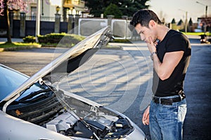 Handsome young man trying to repair a car engine