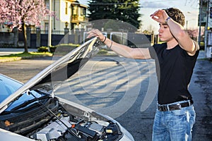 Handsome young man trying to repair a car engine