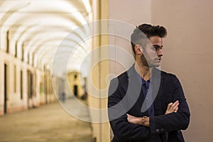 Handsome young man under cloisters in Italian city at night