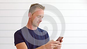 Handsome young man using 5g phone and thinking against a white background with copy space. Trendy guy sending a text