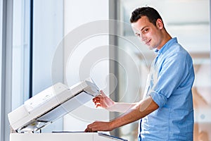 Handsome young man using a copy machine
