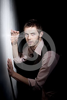 Handsome young man using glass to eavesdrop