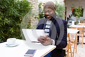 Handsome young man using his digital tablet in the cafe.