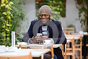 Handsome young man using his mobile phone in the cafe.