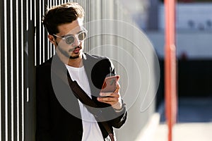 Handsome young man using his mobile phone in the street.