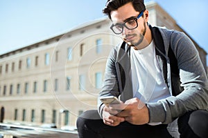 Handsome young man using his mobile phone in the street.