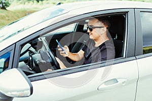 Handsome Young Man using mobile phone while driving a car