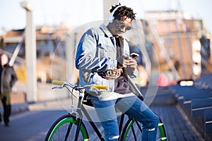 Handsome young man using mobile phone and fixed gear bicycle in the street.
